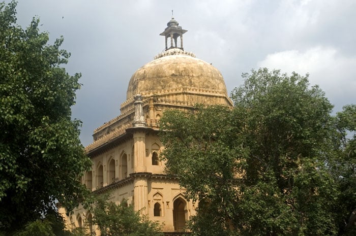 Fateh Jung Gumbad, a Mughal-era tomb in Alwar with a large central dome, arched entrances, and surrounding green trees.