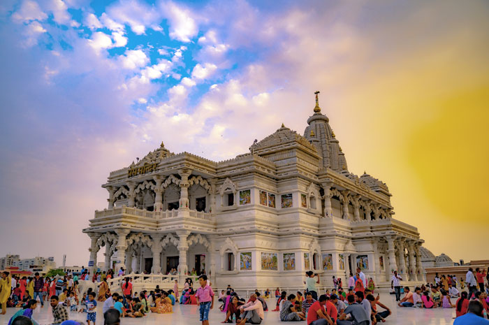 Prem Mandir in Vrindavan featuring intricate white marble architecture, detailed carvings, and visitors gathered in the courtyard at dusk