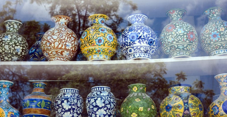 Handcrafted Jaipur blue pottery vases and jars with floral patterns on display in a glass shop window