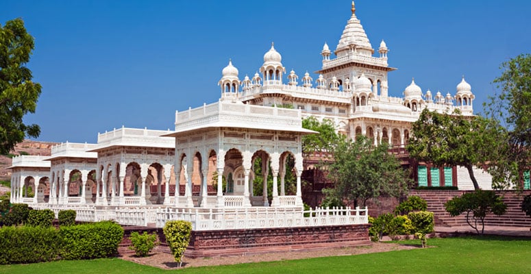 White marble cenotaph of Jaswant Thada with carved arches, dome pavilions, and green lawn in Jodhpur