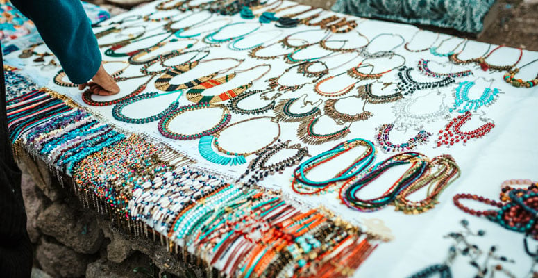 Handcrafted beaded necklaces and colorful gemstone jewelry on display at an outdoor market stall in Jaipur, Rajasthan